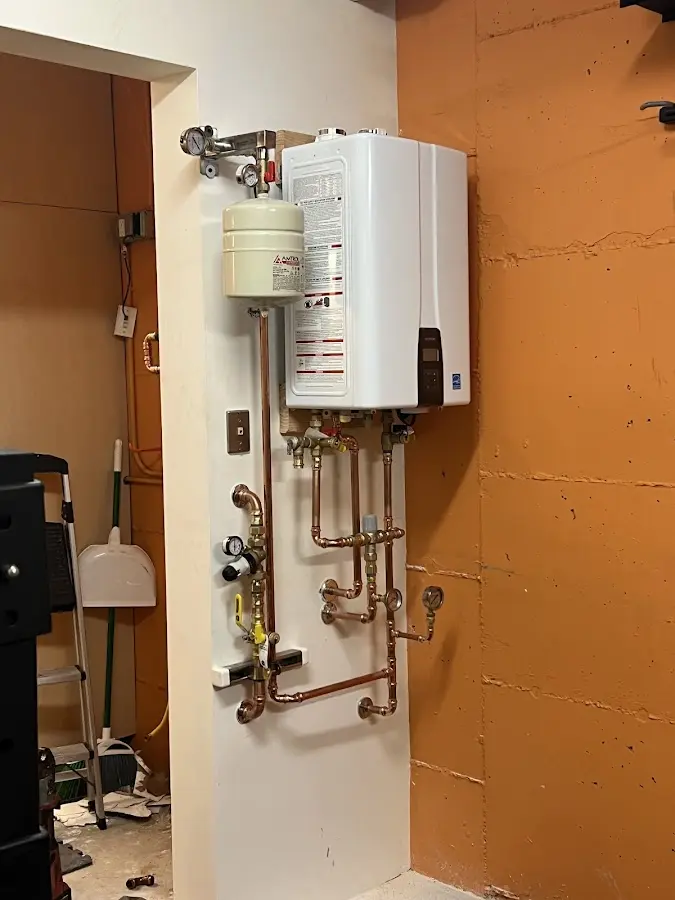 Plumbing technician inspecting water heater connections in Simsbury